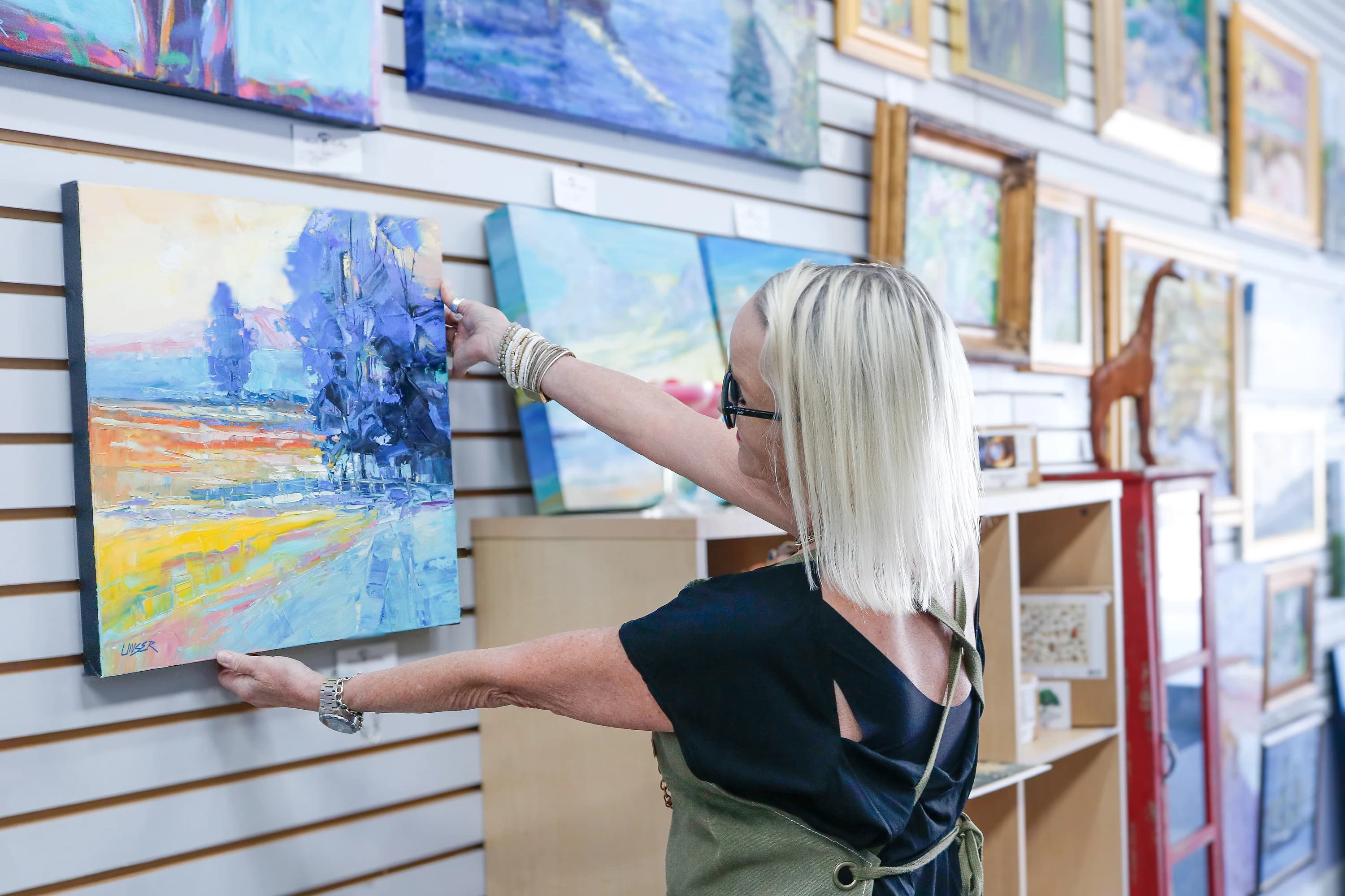 A visitor reaching to look closer at a painting